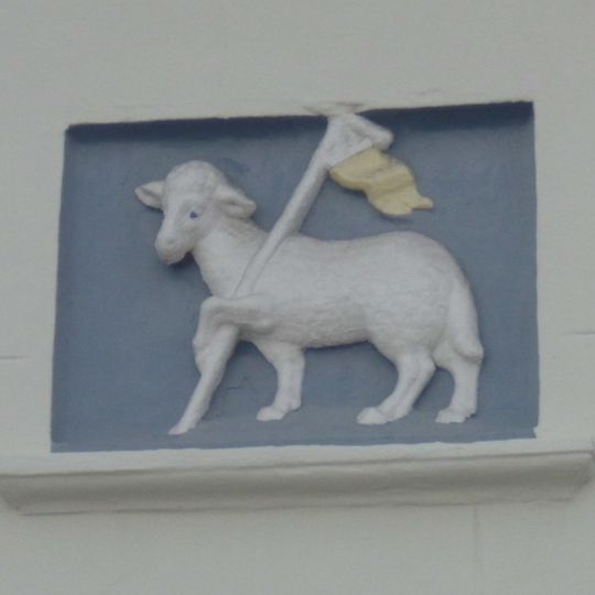 Huis met gepleisterde eenvoudige lage lijstgevel. Gevelsteen met 't Lam Gods. Een geheel met nr 12