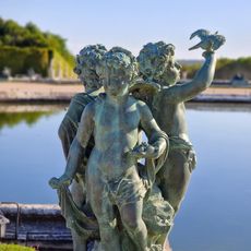 Un Amour tenant un oiseau et deux enfants, dont un assis