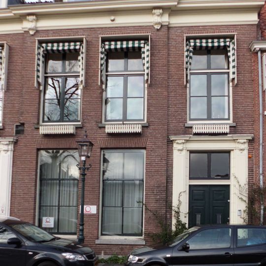 Pand met rechte kroonlijst, vooruitspringend middenrisaliet, twee ingangen met gebeeldhouwde omlijstingen