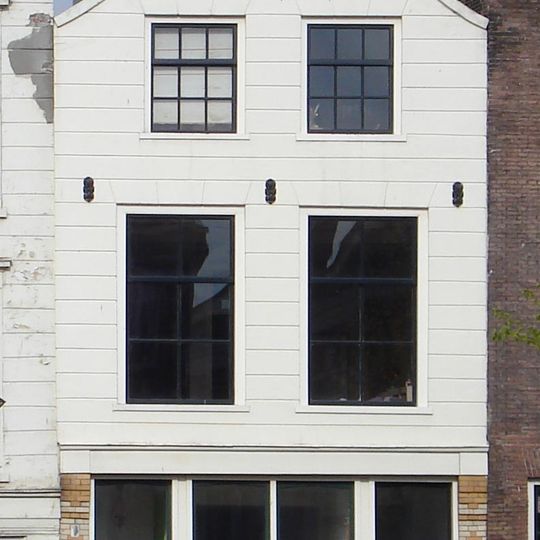 Pand met gepleisterde gevel met inzwenkende zijkanten en in de top drie sierankers