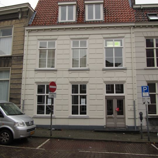 Huis met gebosseerd witgepleisterde lijstgevel en met rode pannen belegd zadeldak