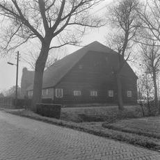 Boerderij, onder hoog, met riet gedekt wolfdak. Uitgebouwde zijkamer met puntgevel. Stal met gepotdekselde houten delen