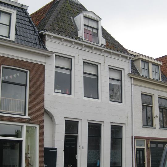 Pand met gepleisterde recht afgesloten gevel onder hoog zadeldak met dakkapel en topschoorsteengevel