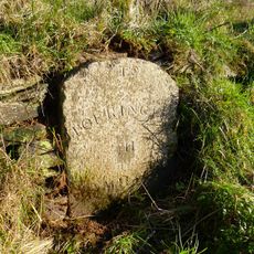 Milestone, S of Fishleigh Cross, on by-pass, 50m S of jct with old road, by path rising up the embankment