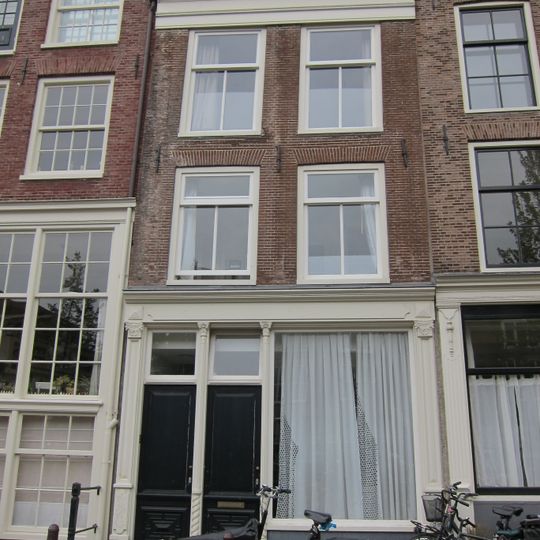 Huis met latere gevel onder rechte lijst waarop een dakkapel in het op het voorste deel van het huis geplaatste dwarse dak