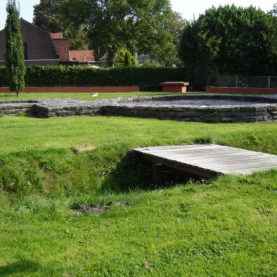 Terrein waarin de fundering van een toegangspoort met aansluitende vestingmuur en sporen van een spitsgracht, een toegangsweg en een brug