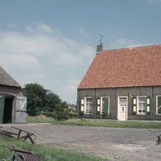 Boerderij, bestaande uit grote schuur- en stal onder een rieten wolfdak, met planken wanden en afzonderlijk woonhuis