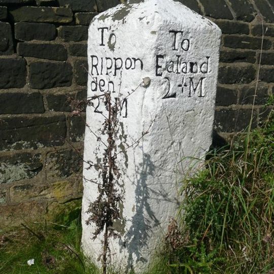 Milestone set against churchyard wall on south west