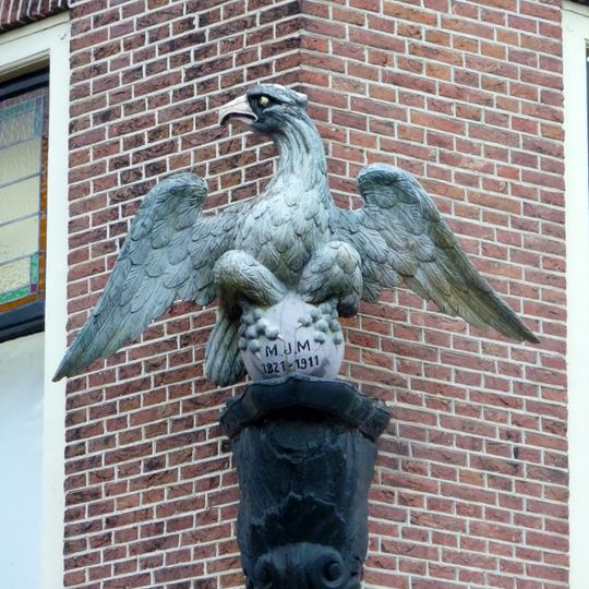 Hoekpand Havenplein. Brede bakstenen lijstgevel. Fraai uithangteken van de voormalige apotheek de "Blauwe Arend".