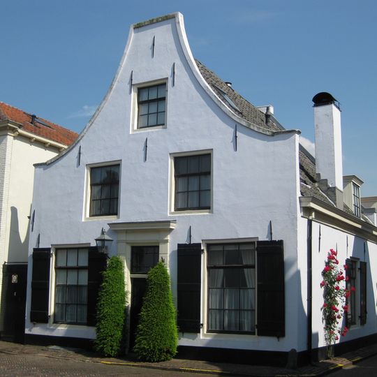 Gepleisterd pand met klokgevel, schuiframen met kleine roeden