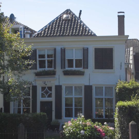 Pand met zolderverdieping en door pannen gedekt schilddak, aan de voorzijde afgewolfd boven de van een houten kroonlijst voorziene gevel van vroeg 19e-eeuws karakter