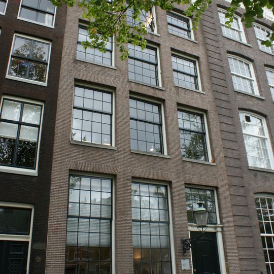 Pand met gevel onder rijk gebeeldhouwde verhoogde zandstenen lijst waarop borstbeelden