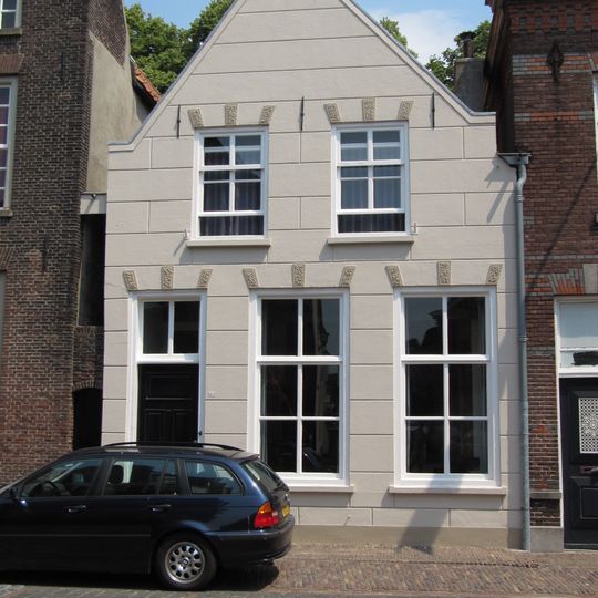 Huis met gebosseerd witgepleisterde topgevel en stoep van gele steentjes