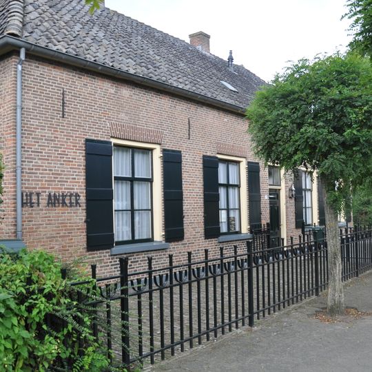 Boerderij waarvan het met een pannen schilddak gedekte woonhuis met de door een wolfdak gedekte stal een T-vormige plattegrond vormt