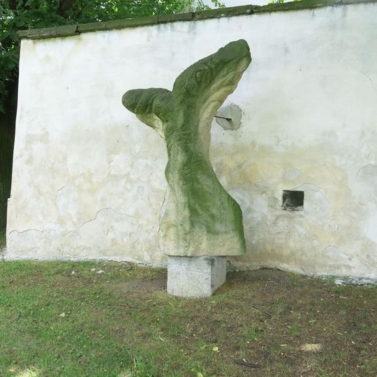 Kamenná plastika Ukřižovaný u zdi areálu kostela v Podlesicích