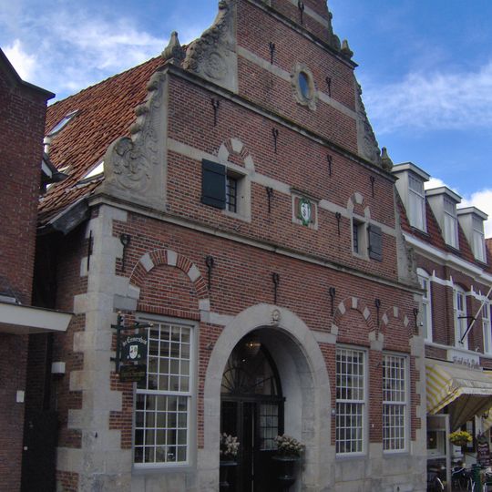 Pand met rijke bakstenen gevel met zandstenen hoekblokken, waterlijsten, gebeeldhouwde klauwstukken en fronton bekroond door pijnappel. Wapensteen met wapens Cremer-Dreesman en jaartal.