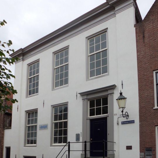 Huis met gepleisterde forse lijstgevel aan de zijkanten iets naar voren springend. 19e-eeuws karakter; echter oudere opzet aanwezig