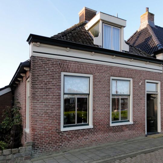 Eenvoudig pand onder zadeldak met voorschild waarboven topschoorsteen en met dakkapel met eenvoudige klauwstukken