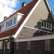 Blok met 8 keukenwoningen, zo genoemd vanwege destijds nieuwe plaatsing van keuken aan de voorzijde, aan de zijkant een houten topgevel, bouwstijl Amsterdamse School.