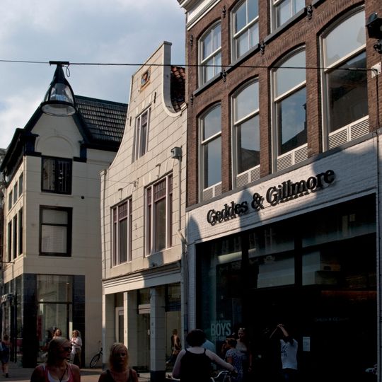 Pand met verminkte gepleisterde klokgevel met gevelsteen en gewijzigde ramen in pui