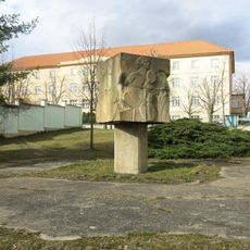 Kamenná plastika mezi domy v ulici Tomanova ve Slaném