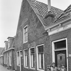 Pand onder zadeldak tegen puntgevel met vlechtingen langs de zijden