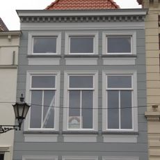 Huis met gebosseerd gepleisterde lijstgevel, lage bovenverdieping en schilddak