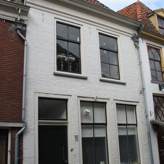 Pand met gepleisterde lijstgevel en deur met geprofileerde latei en ovale panelen