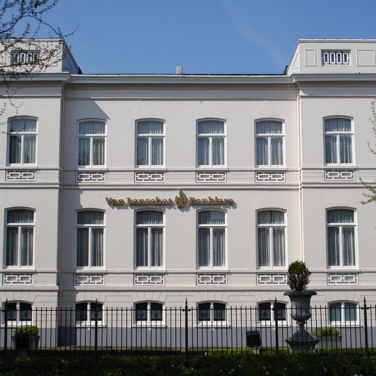 Pand, gepleisterde gevels, risalerende hoekpartijen. In pleister gebosseerde sokkelverdieping. Klassicistisch ornament onder de vensters. Rijk geprofileerde houten kroonlijst rond het gebouw