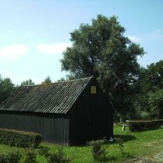 Vrijstaand, houten dijkmagazijn aan de zuidzijde van de dijk