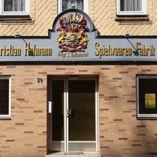 Geschnitzter Wappenschild der Spielwarenfabrik