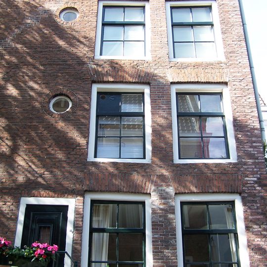 Hoekhuis met halsgevel met geruite gedeelde vleugelstukken en een palmet in de afdekking