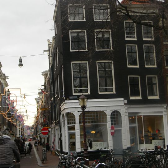 Hoekhuis met voorgevel onder rechte lijst met consoles en gesneden verhoging en boven de gevel van het aangebouwde achterhuis een lijst met consoles