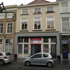 Huis met geelgeverfde lijstgevel en kroonlijst op kleine voluutvormige klossen, schilddak