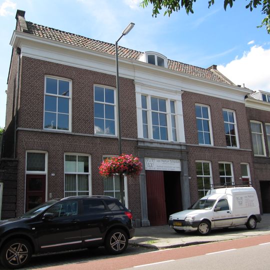 Breed koopmanshuis van parterre en verdieping met brede middenrisaliet, waarin hardstenen poortomlijsting met gebeeldhouwd opschrift "Noord-Holland" en jaartal