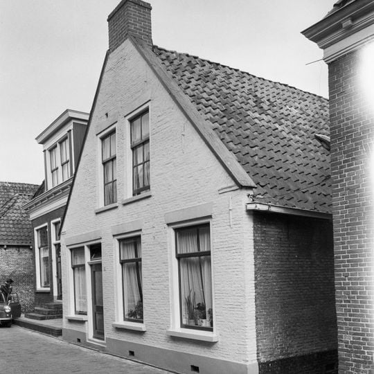 Woning onder zadeldak tegen topgevel met vlechtingen langs de zijden en aanzetlijstje