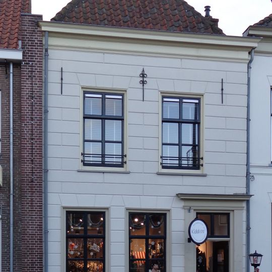 Huis met mooi schilddak en gepleisterde gevel met muurankers onder lijst