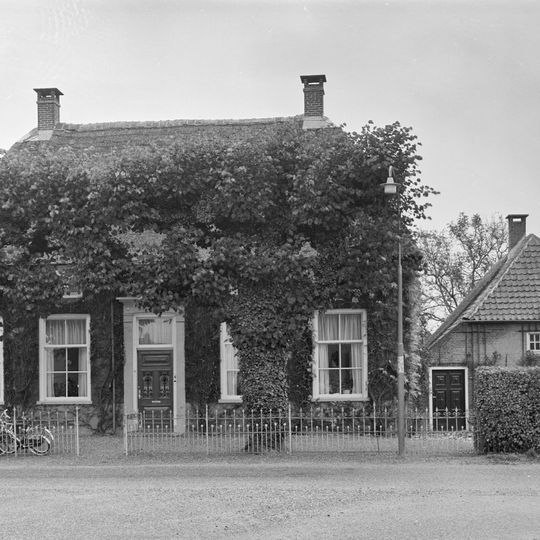 Boerderij op T-vormige plattegrond, waarvan het woonhuis een rieten schilddak draagt en vensters met zesruitsschuiframen bezit. Rechts een zomerhuis, 18e eeuw, onder wolfdak met riet en pannen gedekt