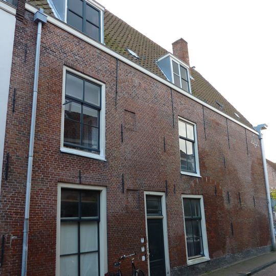 Pand met gepleisterde lijstgevel, zijwand aan de Molensteeg met restanten van vensterbogen en in lichtkleurige baksteen gemetselde Davidster