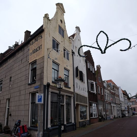 Huis met door driehoekig fronton bekroonde klokgevel en jongere winkelpui