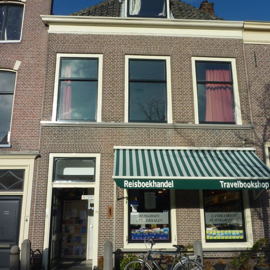 Pand met lijstgevel. Stoephek en palen. Beneden luiken aan de vensters