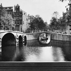 Hoekhuis met halsgevel en een deurpartij in omlijsting en met gebeeldhouwde trapvensters in- en een stoephek tegen de zijgevel