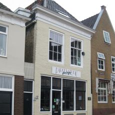 Pand onder zadeldak met achtertopgevel en opgehaalde voorgevel met forse kroonlijst