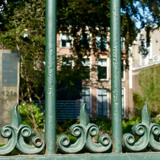 Op laag bakstenen muurtje rustend gietijzeren hek ter afsluiting van binnenstadstuin