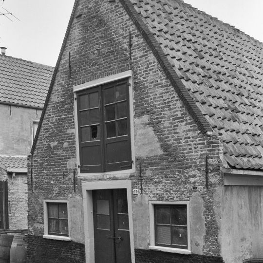 Pakhuisje onder zadeldak met een eenvoudige puntgevel aan de zijde van de achterdam en aan de achterzijde een uit het water van de kooltuin oprijzende puntgevel