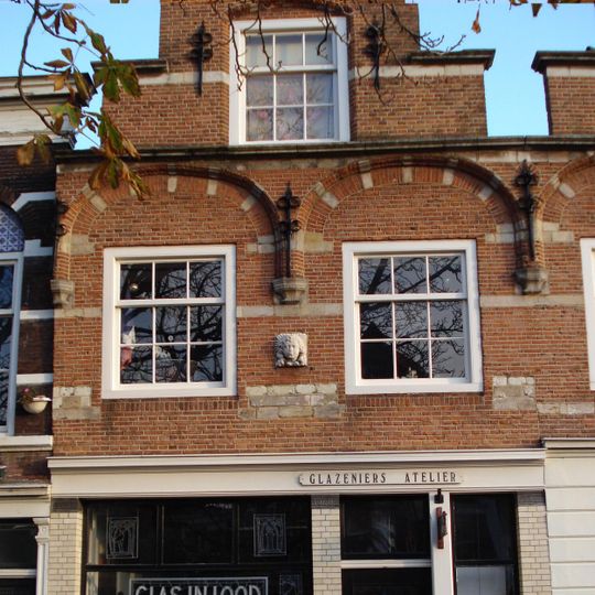 Pand met trapgevel, in Zuidhollandse trant, met uitgekraagde ontlastingsbogen op kraagstenen, natuurstenen banden en sierankers