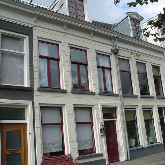 Pand met gepleisterde lijstgevel onder verminkt zadeldak