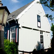 Houten huis op bakstenen onderbouw, tegen de helling opgetrokken