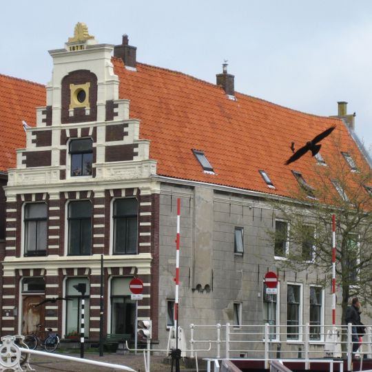 Pand onder diep zadeldak tegen gepleisterde achtertopgevel en moderne voorgevel