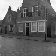 Huis met eenvoudige tuitgevel. Topgevel eindigend in vijf kleine trapjes